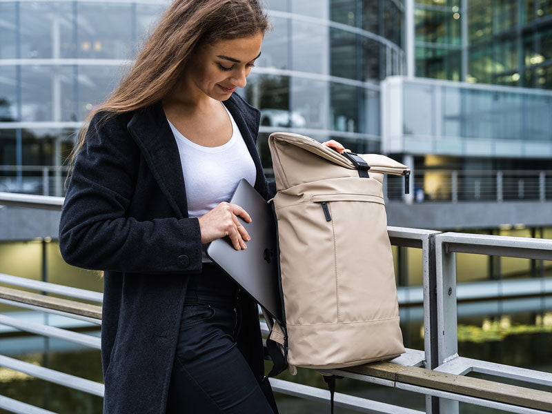 Frau packt Laptop in Rolltop Rucksack ein