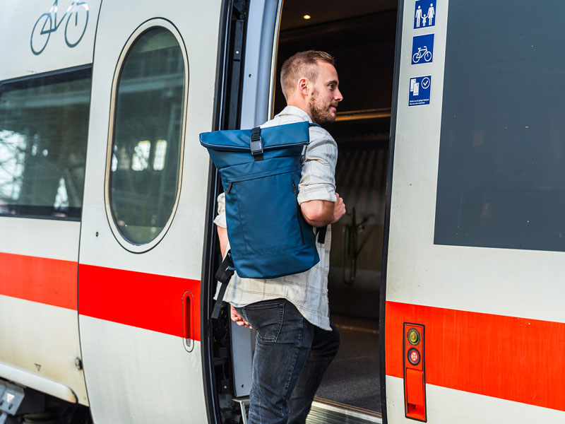 Mann steigt in Zug mit Rucksack auf Rücken