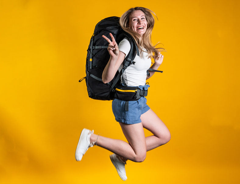 Frau springt mit Backpacking Rucksack