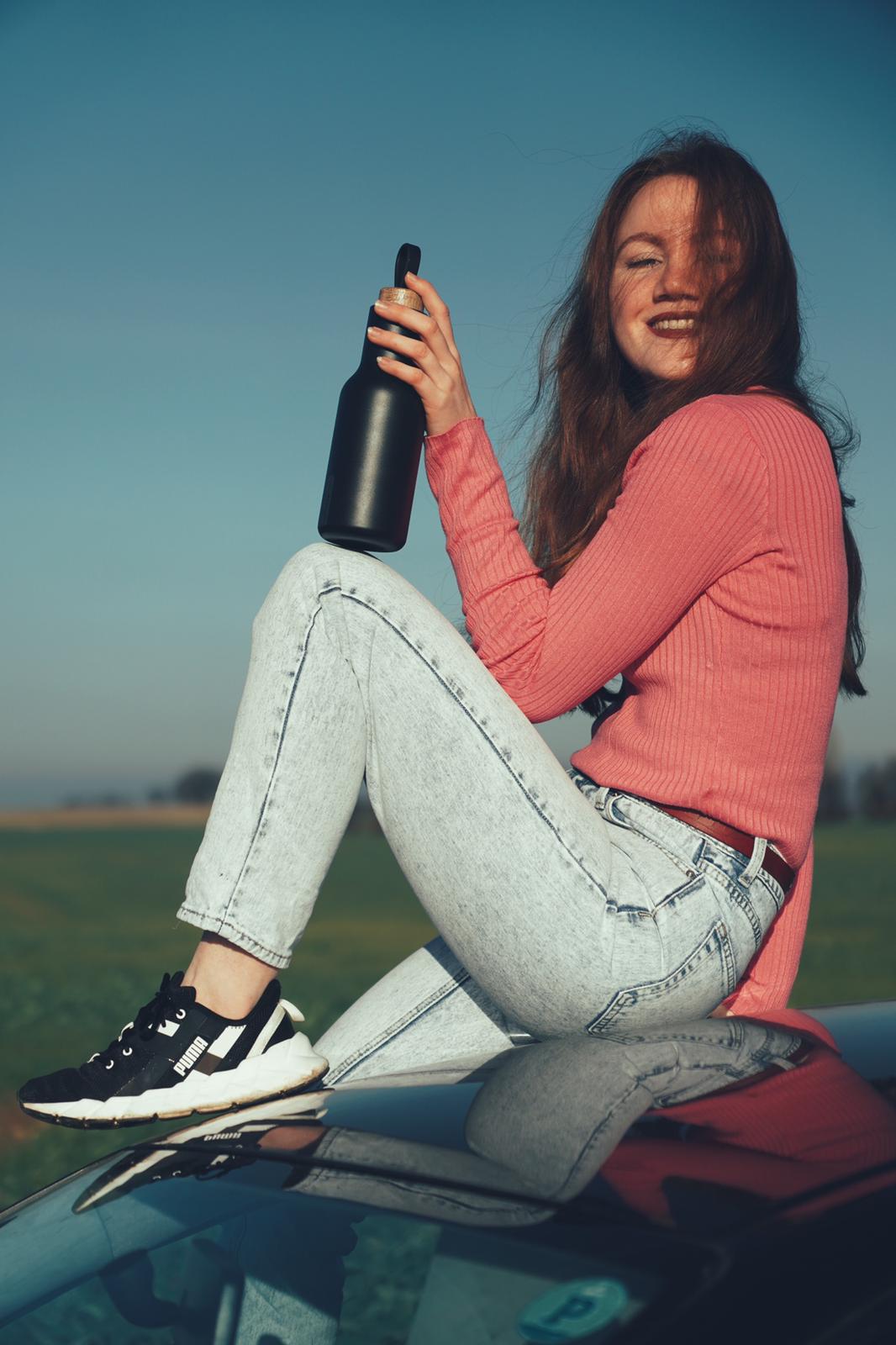 Frau lächelt und hält Trinkflasche aus Edelstahl